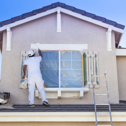 Busy House Painter Painting the Trim And Shutters of A Home. Busy House Painter Painting the Trim And Shutters of A Home.